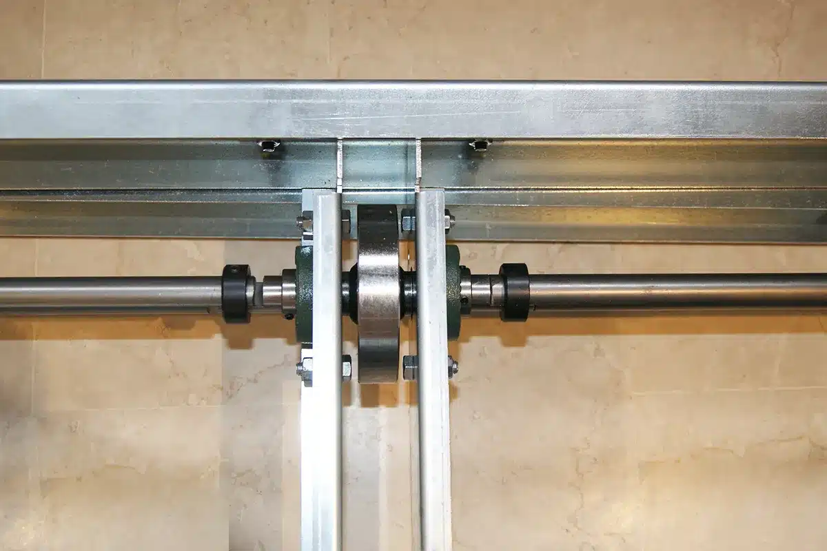 Détail de rayonnage mobile, arbre moteur et roues sur un châssis mobile, aménagement pour une entreprise de BTP en région Rhône-Alpes